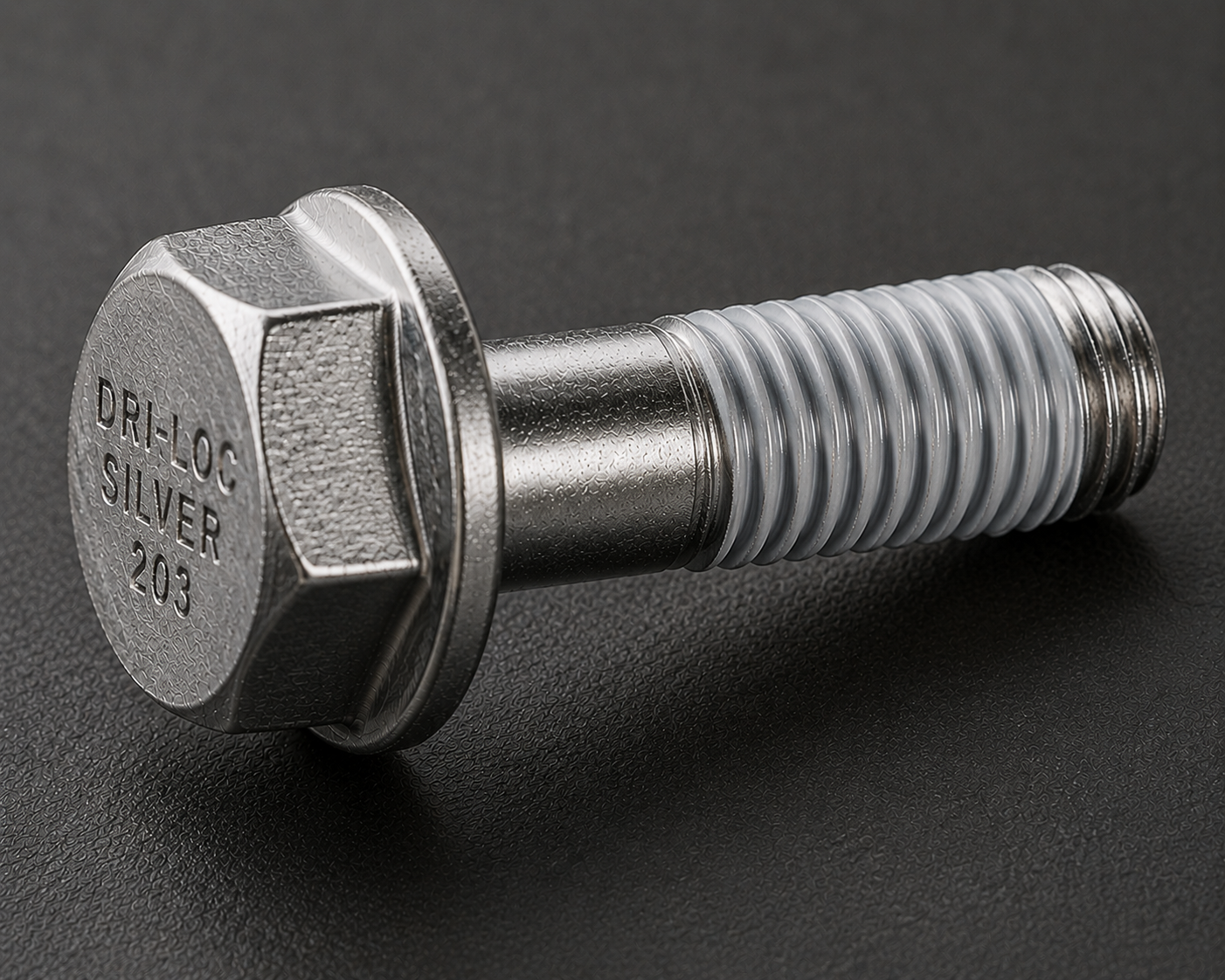 A close-up of a silver metal hex bolt with the text "DRI-LOC SILVER 203" engraved on the head, lying on a black surface. The threads have a translucent coating.